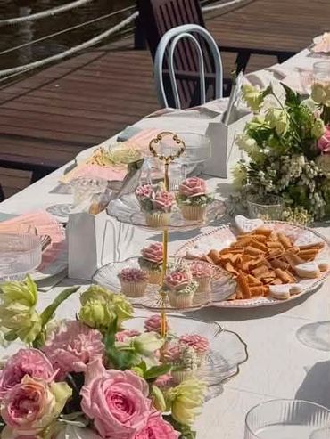 Elegant table setting with flowers, cupcakes, and snacks.