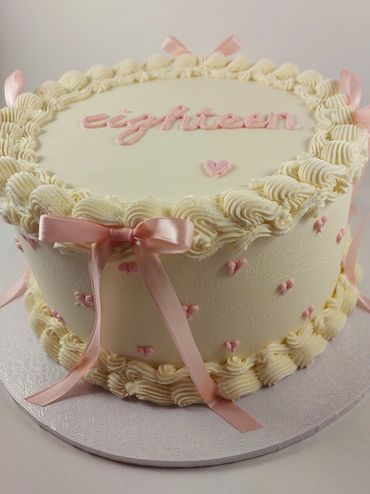 White and pink buttercream vintage style eighteenth birthday cake with pink bows 