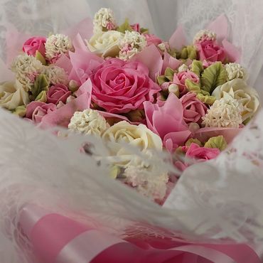 Elegant bouquet of pink and white roses wrapped in delicate lace and pink ribbons.