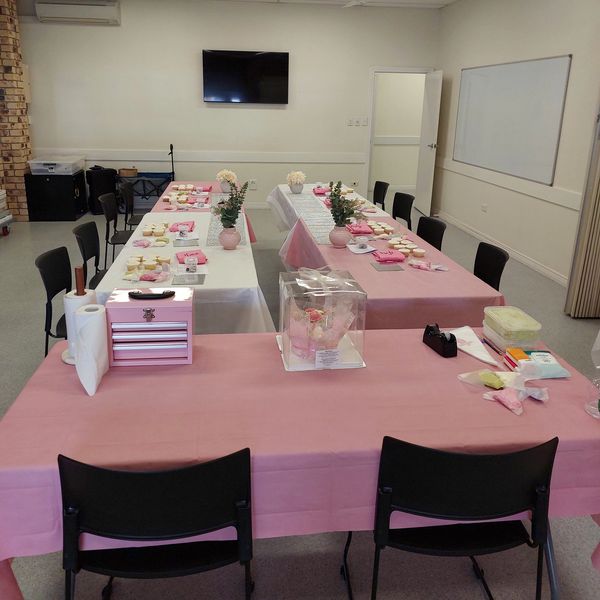 Two tables set for an event with pink and white decorations.