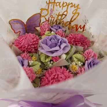 A colorful birthday bouquet with pink and purple flowers and a purple ribbon.