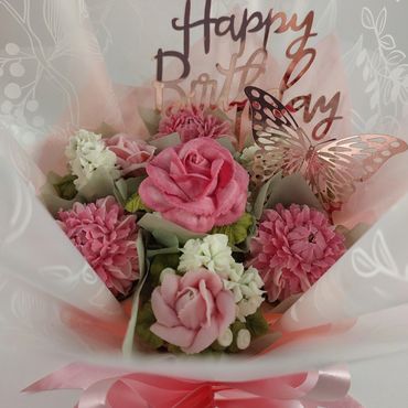 A pink-themed birthday bouquet with flowers and a butterfly decoration.