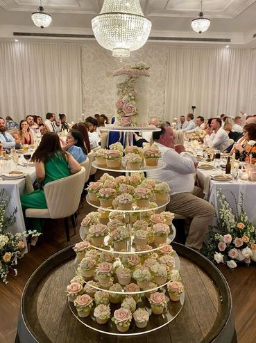 Elegant tiered cupcake display with floral decorations at a formal event.