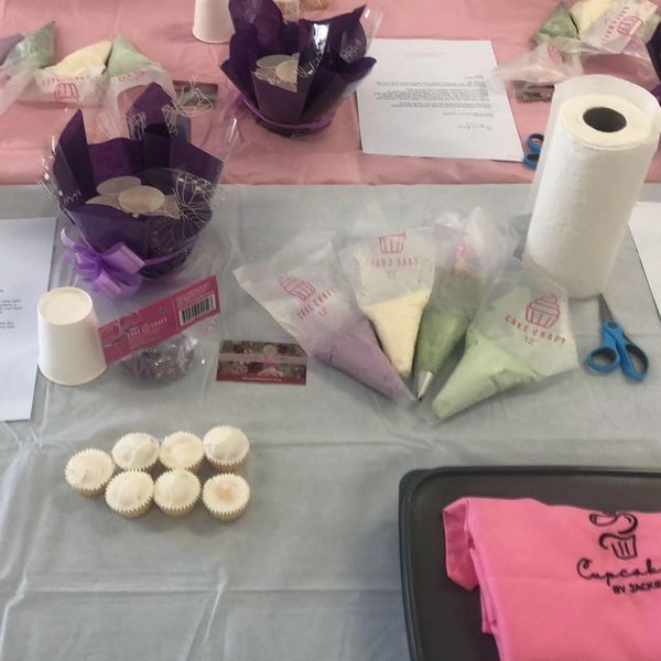 Cupcake decorating setup with frosting bags and paper cups.