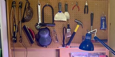 A pegboard with various hand tools and a blue desk lamp.