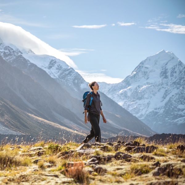 A woman hiking in a mountainous landscape with snow-capped peaks.