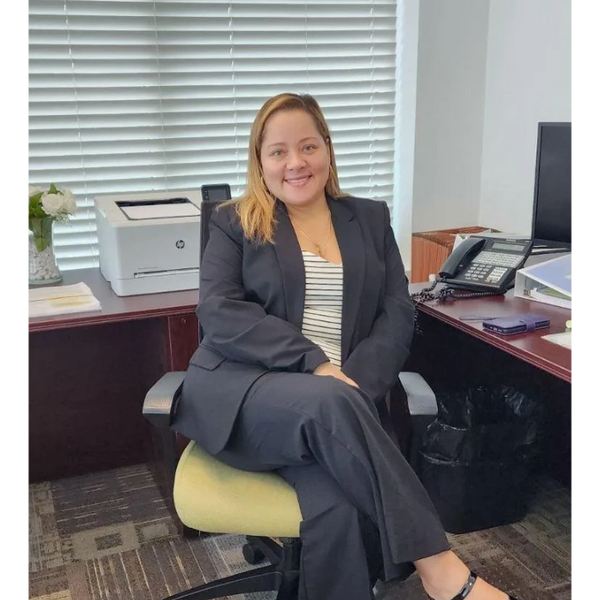 Professional woman in black suit sitting confidently in an office chair.