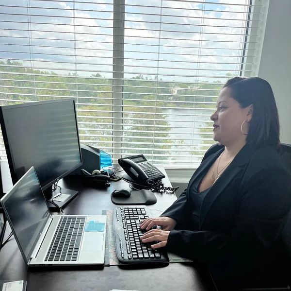 A woman working on a computer at an office desk with a scenic window view.