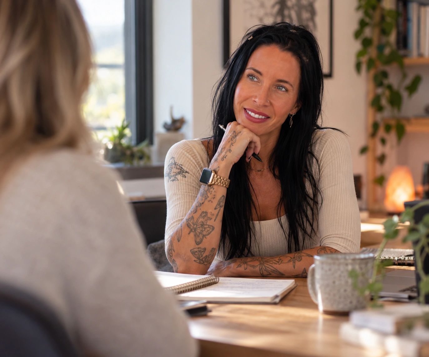 Woman with tattoos listening attentively during a meeting.