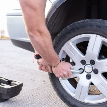 Person using a wrench to tighten car wheel lug nuts.