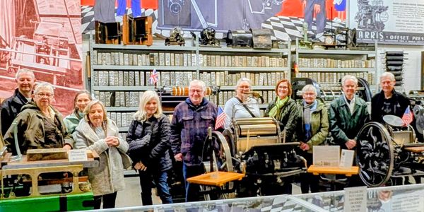 Group of people posing in a printing museum with vintage presses.