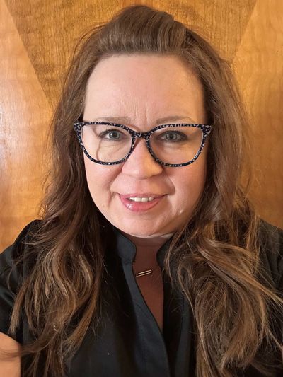 Smiling woman with glasses and long brown hair.