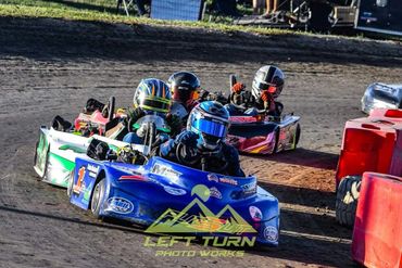 Four go-kart racers navigate a dirt track, closely competing in a thrilling race.