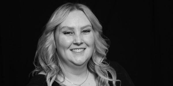 Smiling woman with wavy blonde hair in black and white photo.