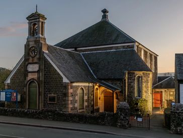 Historic stone church with a clock tower at dusk.