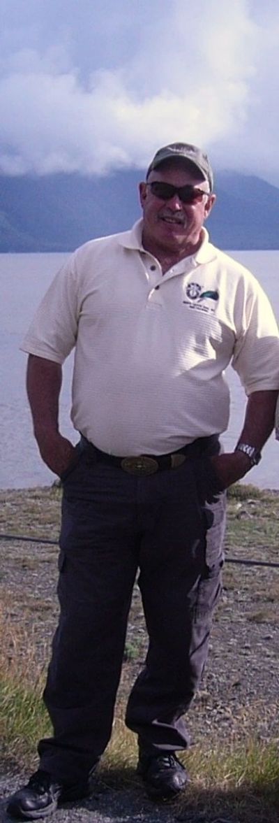 A man wearing a white top, jeans, a cap, and sunglasses