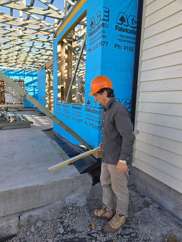 Construction worker measuring concrete slab at building site with a level tool.