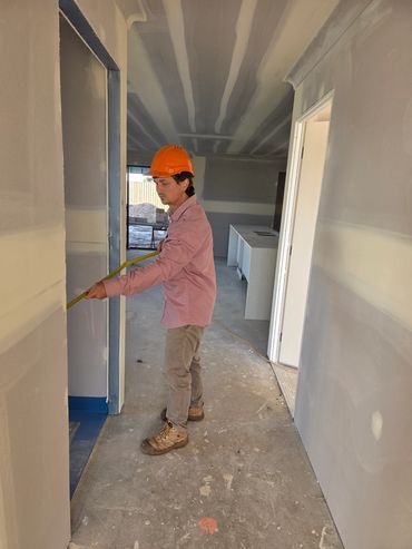 Construction worker measuring a doorway inside a building under construction.