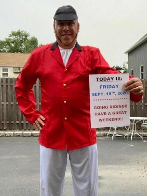 Man in red jacket holds a sign about a Friday ride on Sept 18, 2020.
