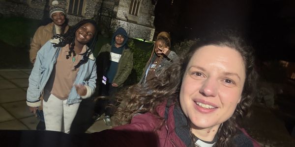 Group selfie of five friends outdoors at night, smiling and enjoying.