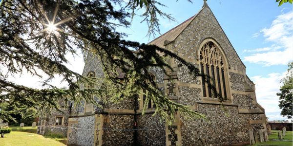 Sun shining through tree branches near a stone church.