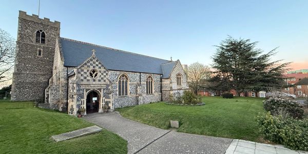 Historic stone church building with a tall tower and arched windows on a green lawn.