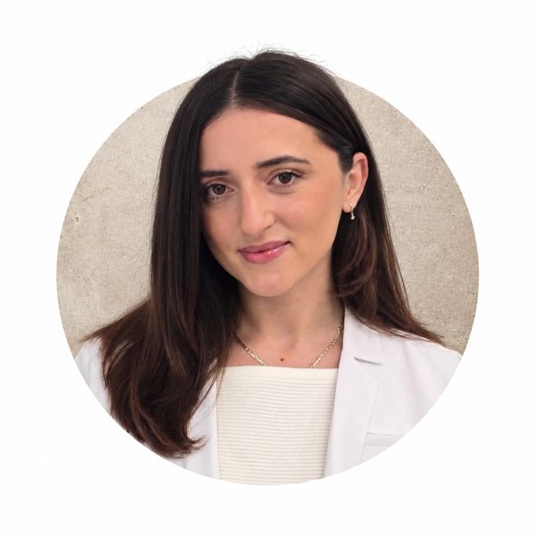 Young woman with long brown hair in a white blazer.