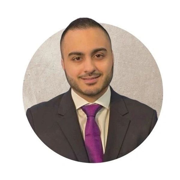 Man in a suit with a purple tie smiling