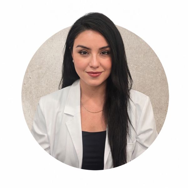 Portrait of a woman in a white lab coat with long dark hair.