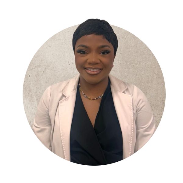 Smiling woman in a white blazer and black top against a neutral background.