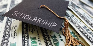 Graduation cap labeled 'Scholarship' resting on hundred-dollar bills.