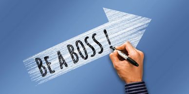 Hand writing 'BE A BOSS!' on a blue arrow background.