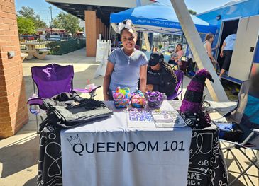 Woman at a Queendom 101 informational booth outdoors.