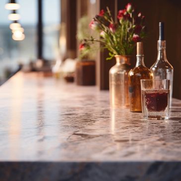 A beautiful bar with white marble countertops, with liquor bottles and flowers on top.