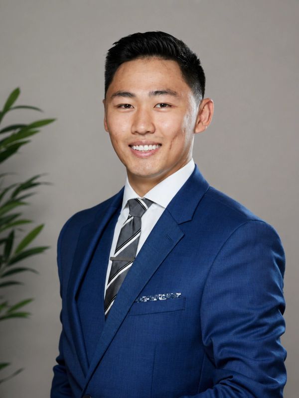 Young man in blue suit smiling for a professional headshot.