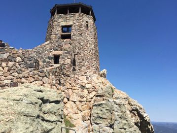 Black Elk Peak tower with mountain goat balanced on the granite rocks. Formerly Harney Peak.