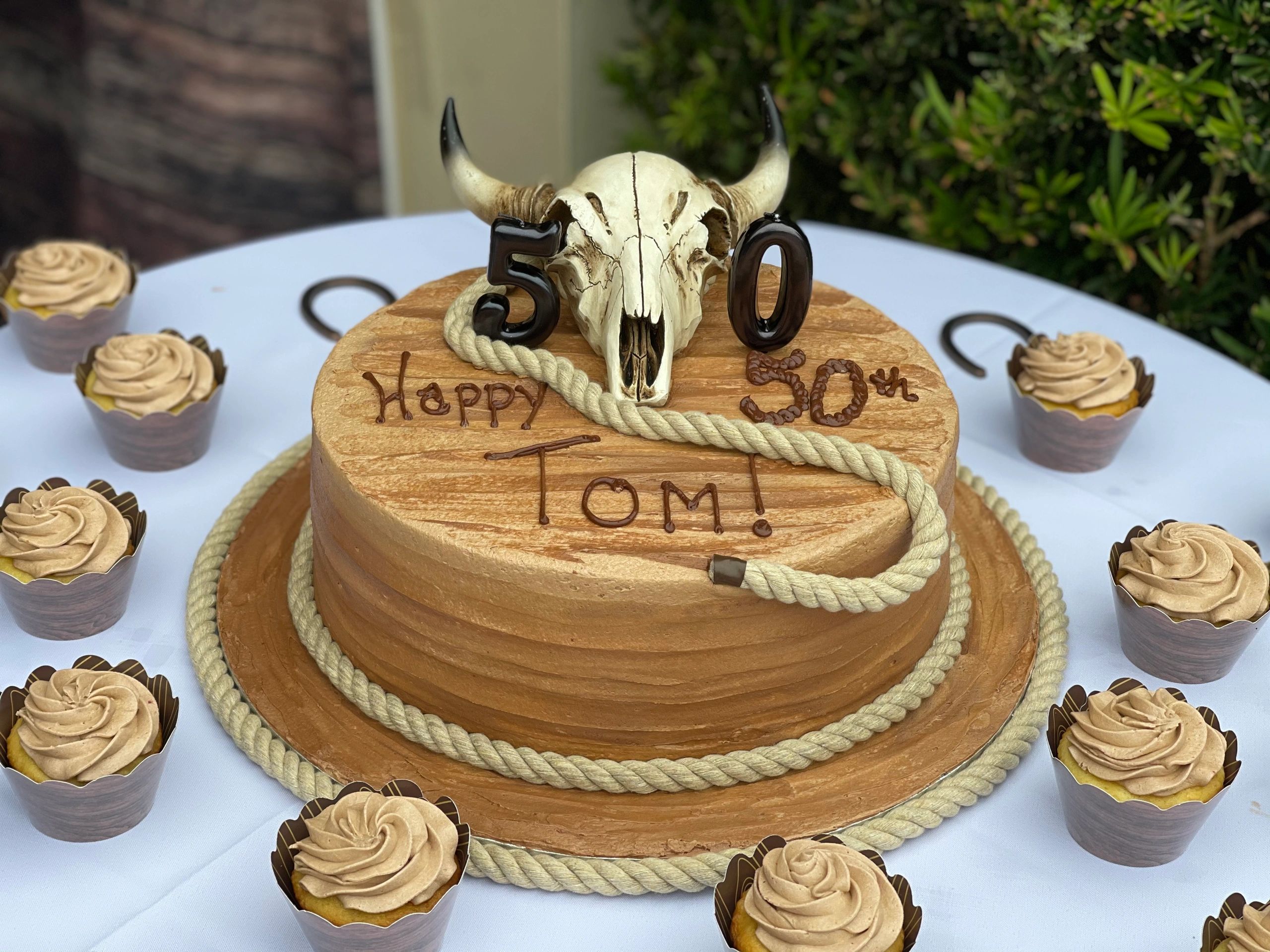Rustic 50th birthday cake with cow skull and rope details.