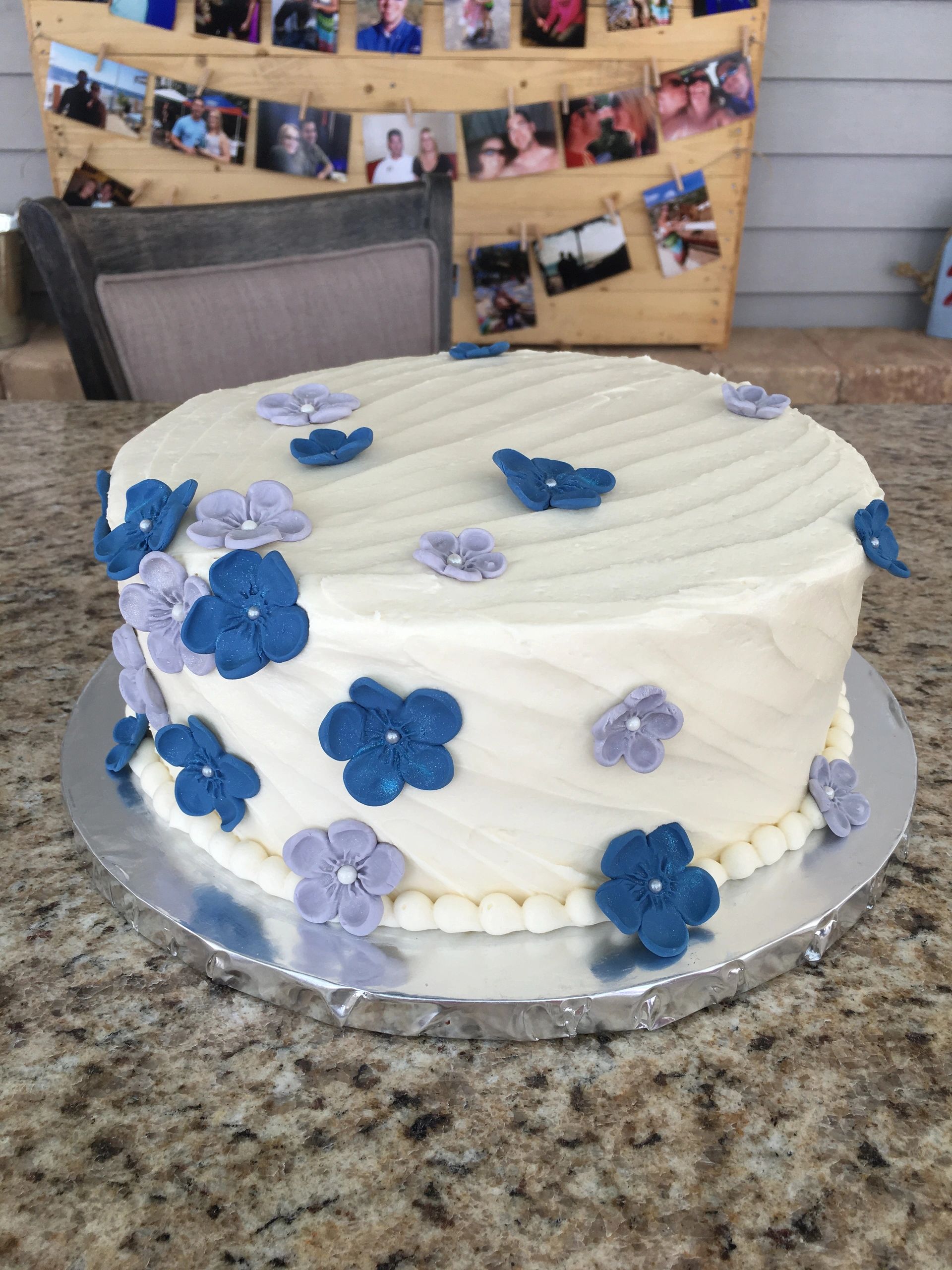 White cake with blue and purple fondant flowers.