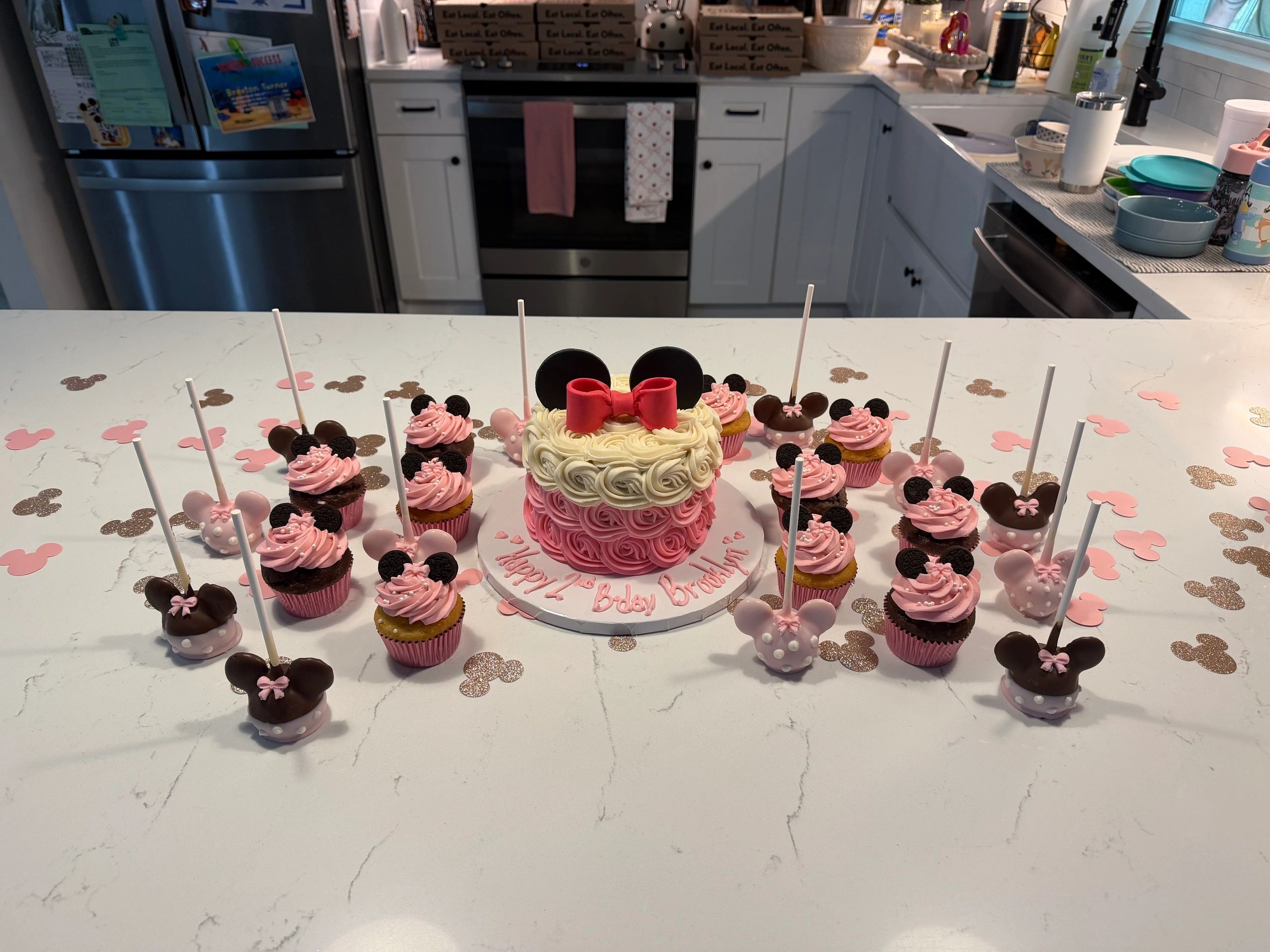 Minnie Mouse themed birthday cake and treats on kitchen counter.