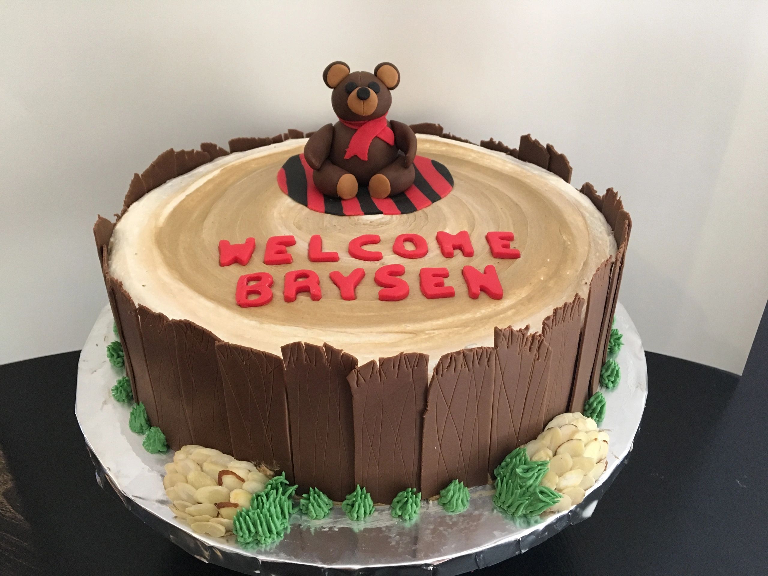 A wood-themed cake with a teddy bear figure and red lettering.