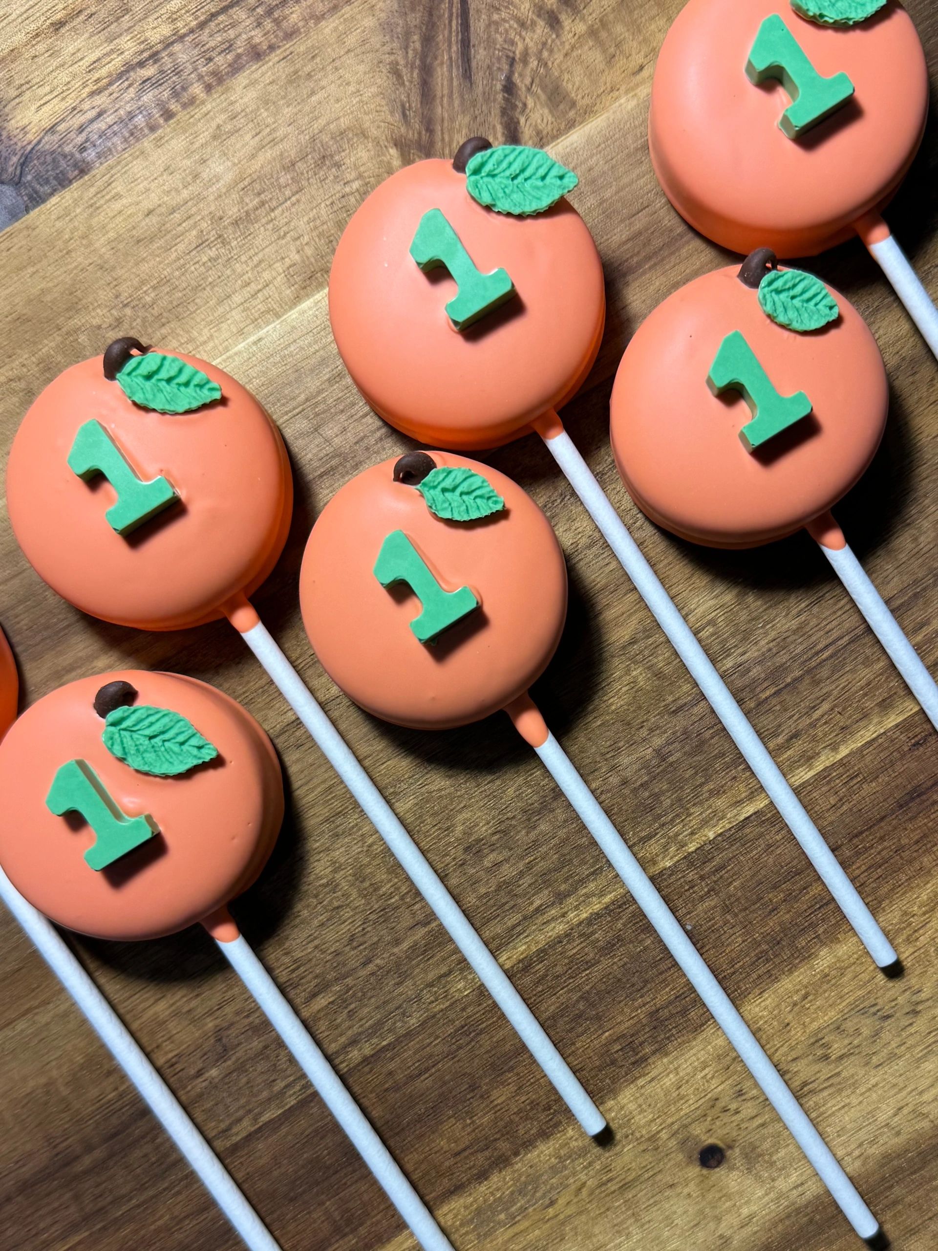 Pumpkin-themed cake pops with green number 1 toppers.