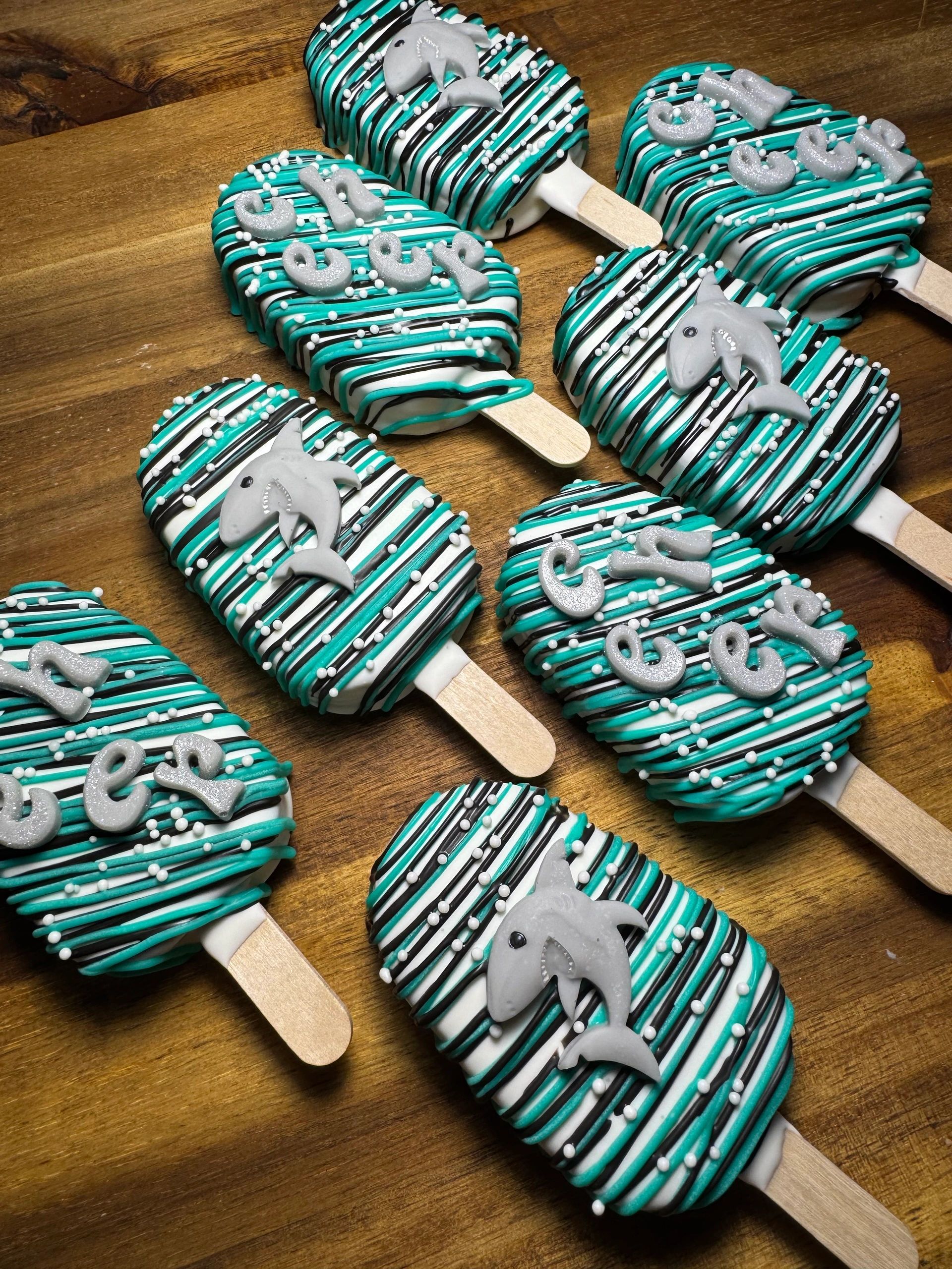 Decorated popsicles with teal, black, and white stripes and shark figures.