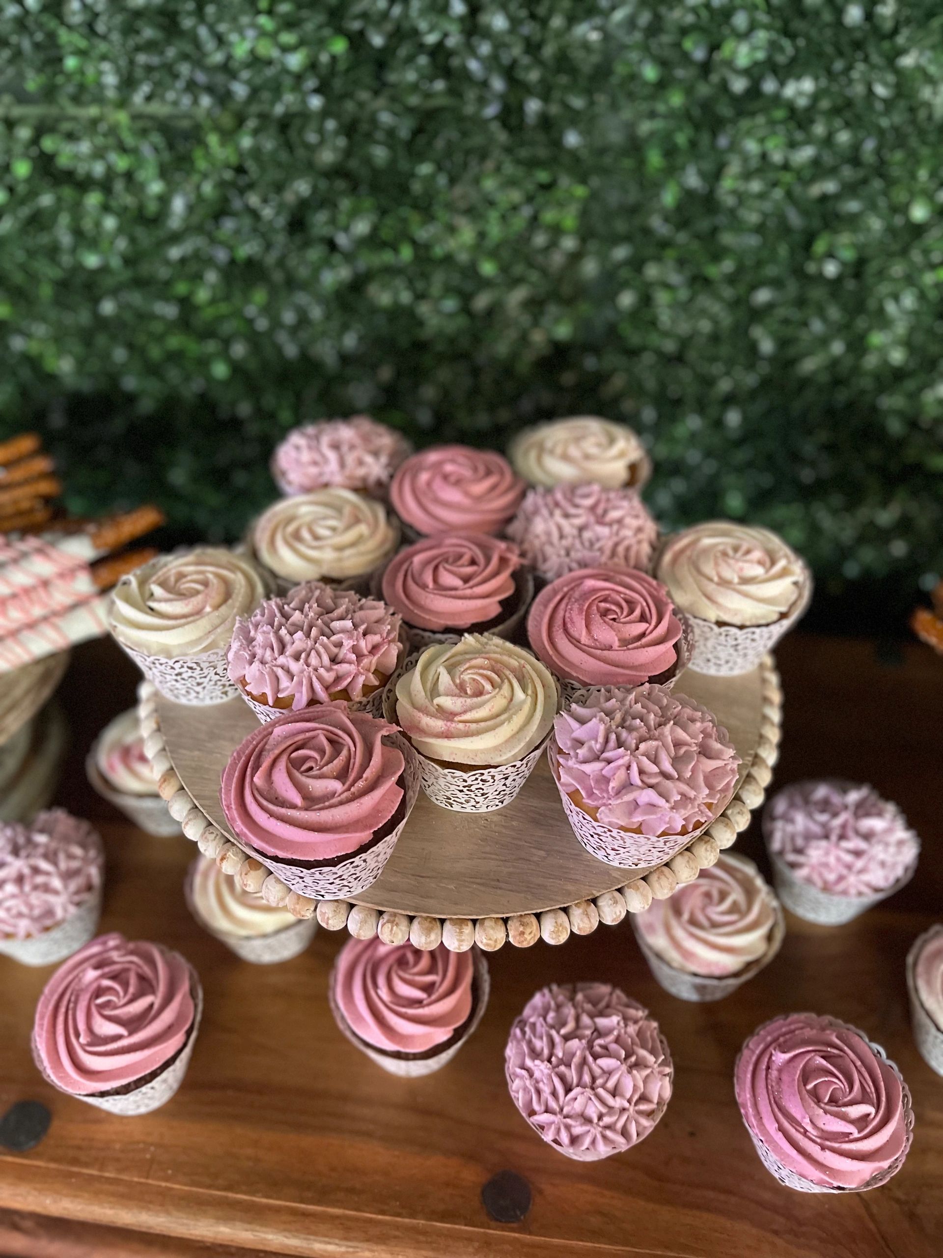 Cupcakes with pink and cream frosting on a wooden stand.