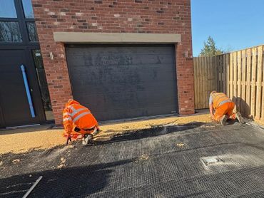 Employees working together to get a driveway complete outside of the garage door.