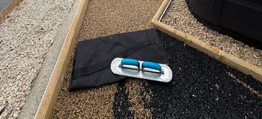 A black resin surface in a garden with the new sand colour resin being applied.