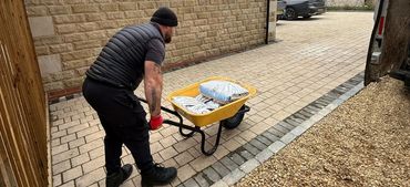 Employee loading a wheel barrow of items to carry part of the garden.