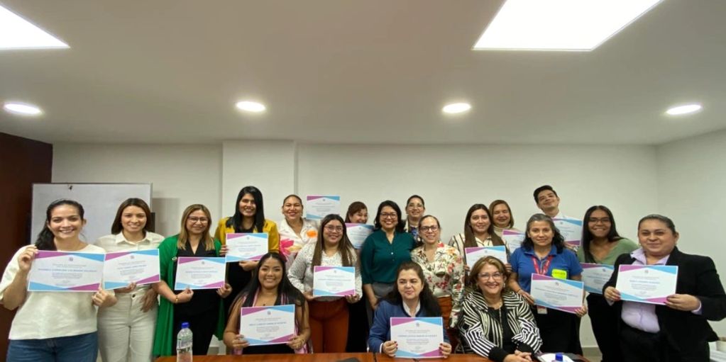 Group of people holding certificates in a classroom setting.