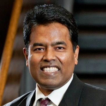 Smiling man in a suit and tie posing indoors.