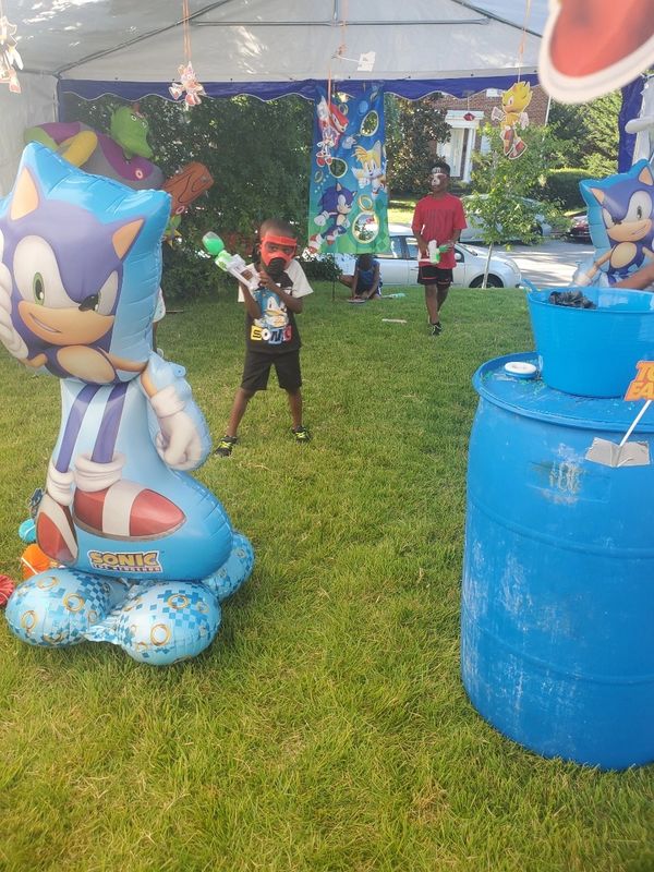 Kids enjoying a Sonic-themed outdoor water gun game under a tent.