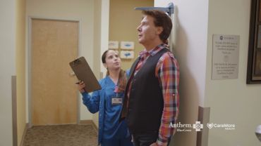 Healthcare worker measuring a man's height in a clinical setting.